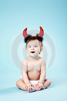 Baby with devil horns on blue background