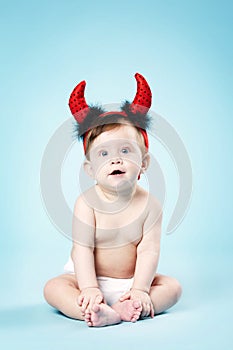 Baby with devil horns on blue background