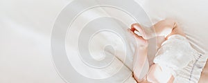 Baby in a diaper lies on a white bed. top view. copy space