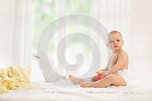 Baby in diaper playing with rubber toy