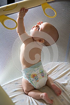 Baby in a diaper in playpen