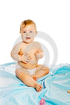 Baby in diaper sitting on a blue blanket. Isolated