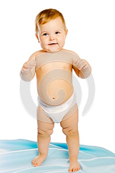 Baby in diaper standing on a blue blanket. Studio. Isolated