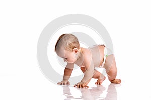 Baby in diapers crawling on white studio floor