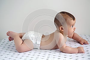 Baby in diapers lying on her belly