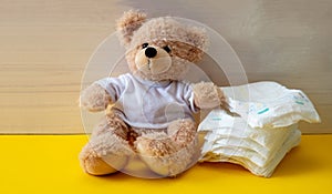 Baby diapers and teddy on yellow color floor