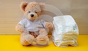 Baby diapers and teddy on yellow color floor