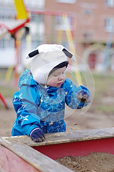 Baby with dirty hands plays in sandpit