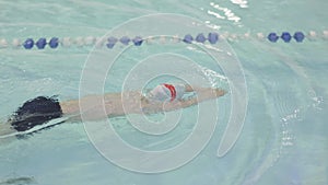 baby diving, moving legs under water during swim class in swimming pool learning