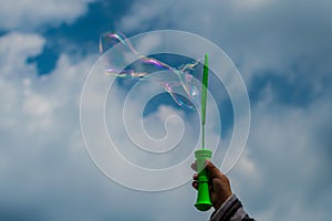 Baby doing soap bubbles - hand on sky, clouds background.