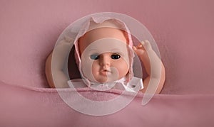 Baby doll toy photodraphed in a newborn style. Wrapped in pink woolen fabric and lacy cap