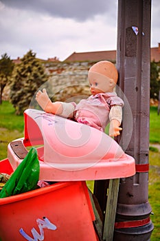 Baby doll toy on a trash can