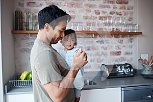 Baby, down syndrome and father holding and bonding with child in a kitchen, learning to care for special needs newborn