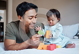 Baby, down syndrome and learning on a bed with child and father playing with educational blocks in a bedroom. Family