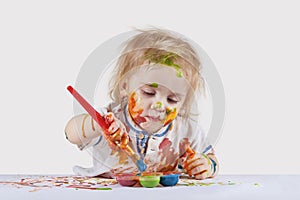 The baby draws on paper with finger paints. Children\'s pranks photo