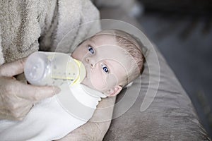Baby drinking from bottle with nipple in mouth photo