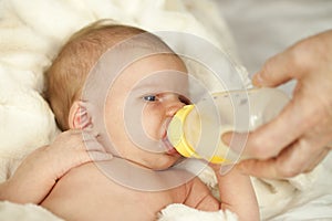 Baby drinking from bottle with nipple in mouth