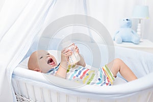 Baby drinking milk. Boy with formula bottle in bed