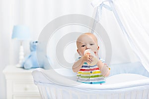 Baby drinking milk. Boy with formula bottle in bed