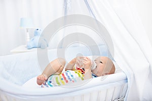 Baby drinking milk. Boy with formula bottle in bed