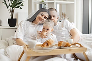 Baby drinking from sippy cup while parents snuggling at home