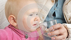 Baby drinking water from glass from mother`s hand