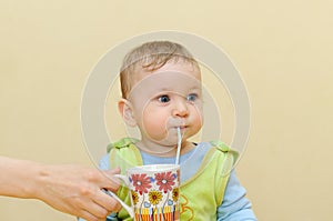 Baby drinks juice through a straw