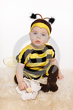 Baby earing bee costume sitting on the floo