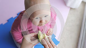 Baby eating avocado from mother`s hands.