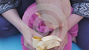 Baby eating banana from hands of mother