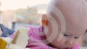 Baby eating banana from hands of mother