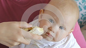 Baby eating banana from hands of mother