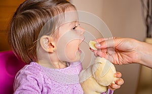 Baby eating banana slice from the hand of mother