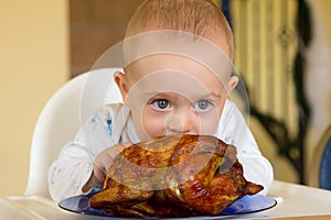 Baby eating a big grilled chicken