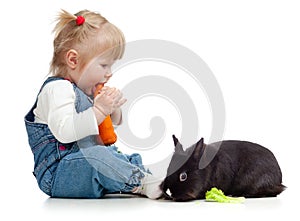 Baby eating a carrot and feeding rabbit