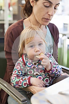 Baby eating chips on mother legs