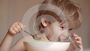 Baby eating. Cute child eating breakfast at home. Portrait of sweet little laughing baby boy with blonde hair eating