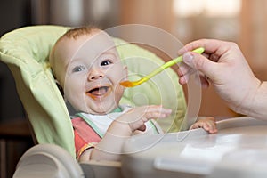 Baby eating food with father help