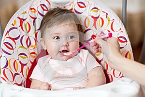 Baby eating food with mother help