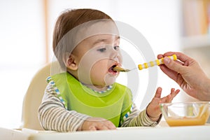 Baby eating food with mother help