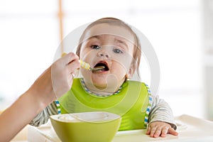 Baby eating food with mother help