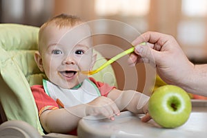 Baby eating healthy food with father help at home