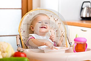 Baby eating healthy food on kitchen