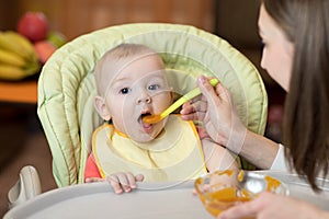 Baby eating healthy food with mother help at home