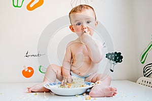 Baby eating by himself learning through the Baby-led Weaning method, exploring the flavors of food with curiosity