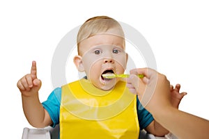 Baby eating spoon baby food jar. Child feeding.