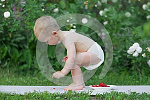 Baby eats strawberries and raspberries. Toddler face in food close-up