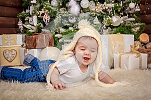 Baby in elf costume playing with old wooden train and soft toy bears under the Christmas tree, vintage.