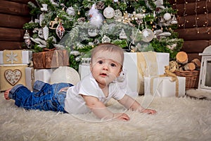 Baby in elf costume playing with old wooden train and soft toy bears under the Christmas tree, vintage.