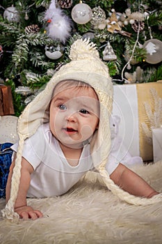 Baby in elf costume playing with old wooden train and soft toy bears under the Christmas tree, vintage.